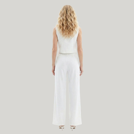 Woman wearing a white sleeveless top and wide-leg pants on a light gray background