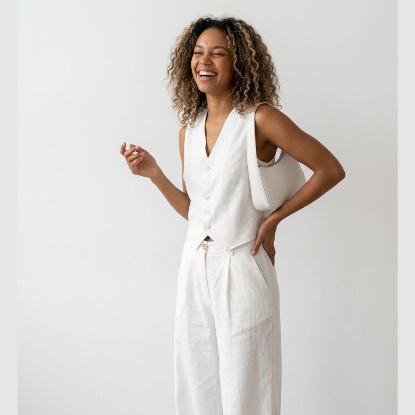 Woman wearing a white sleeveless top and pants against a light gray background